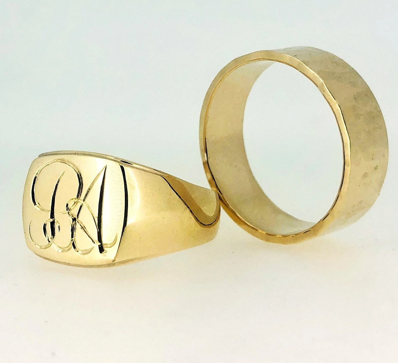 A gold signet ring with initials 'CK' engraved on it.