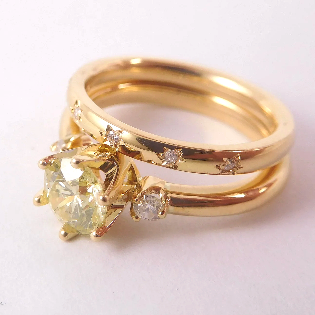 Close-up of a gold ring set with a large yellow center diamond, flanked by two smaller diamonds, and adorned with smaller diamonds along the band.