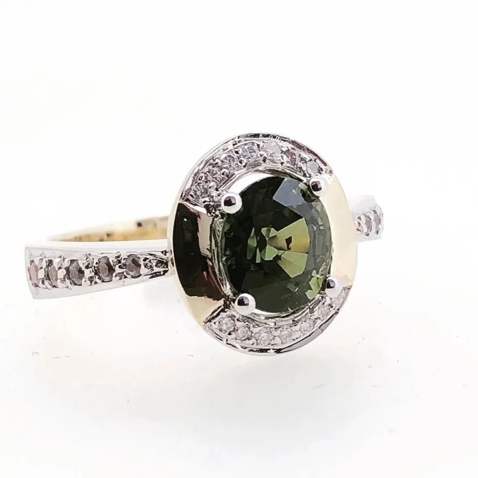 White gold ring with a large dark green gemstone in the center, surrounded by small clear stones.