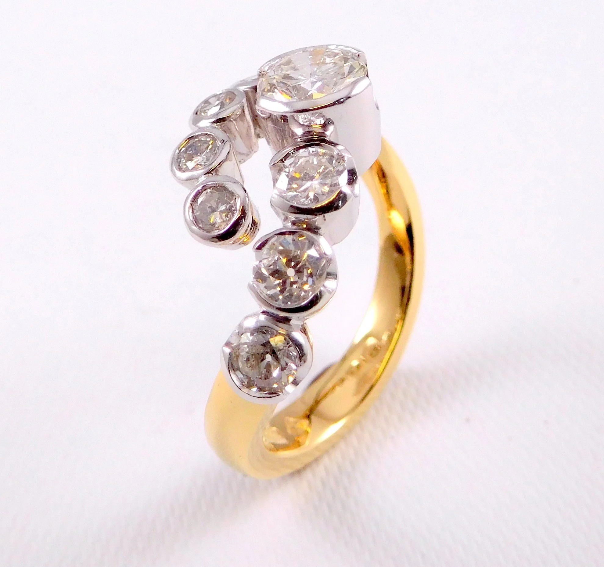A gold ring with multiple diamonds set along the top of the band, reflecting light against a white background.