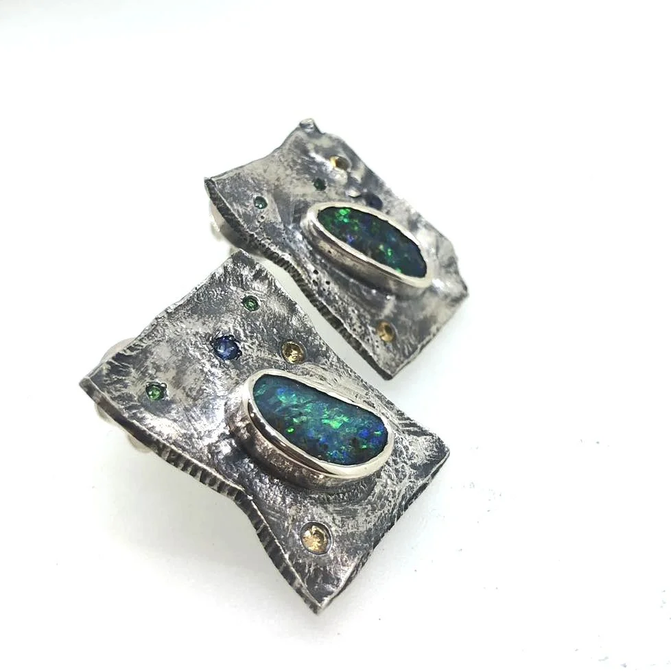 Silver earrings with rectangular shape, featuring green and blue opal stones and small round colorful gemstones.