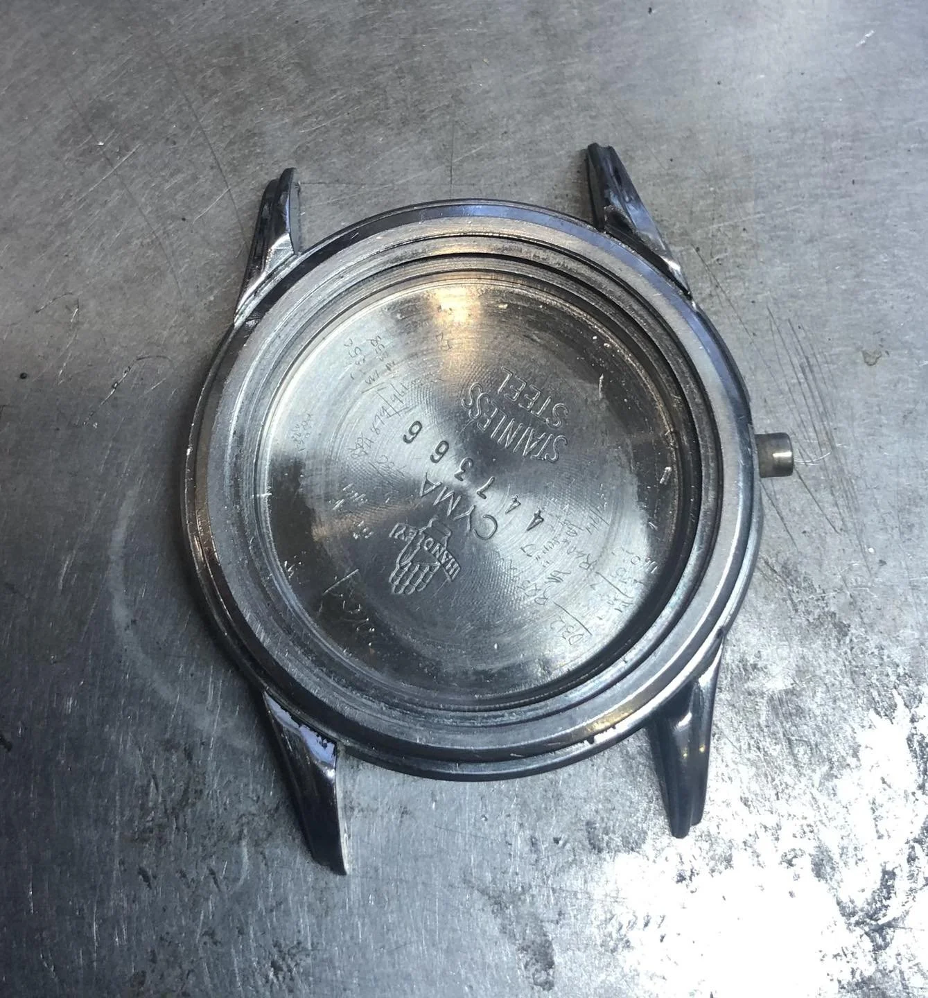 Back of a stainless steel wristwatch with engraved text.