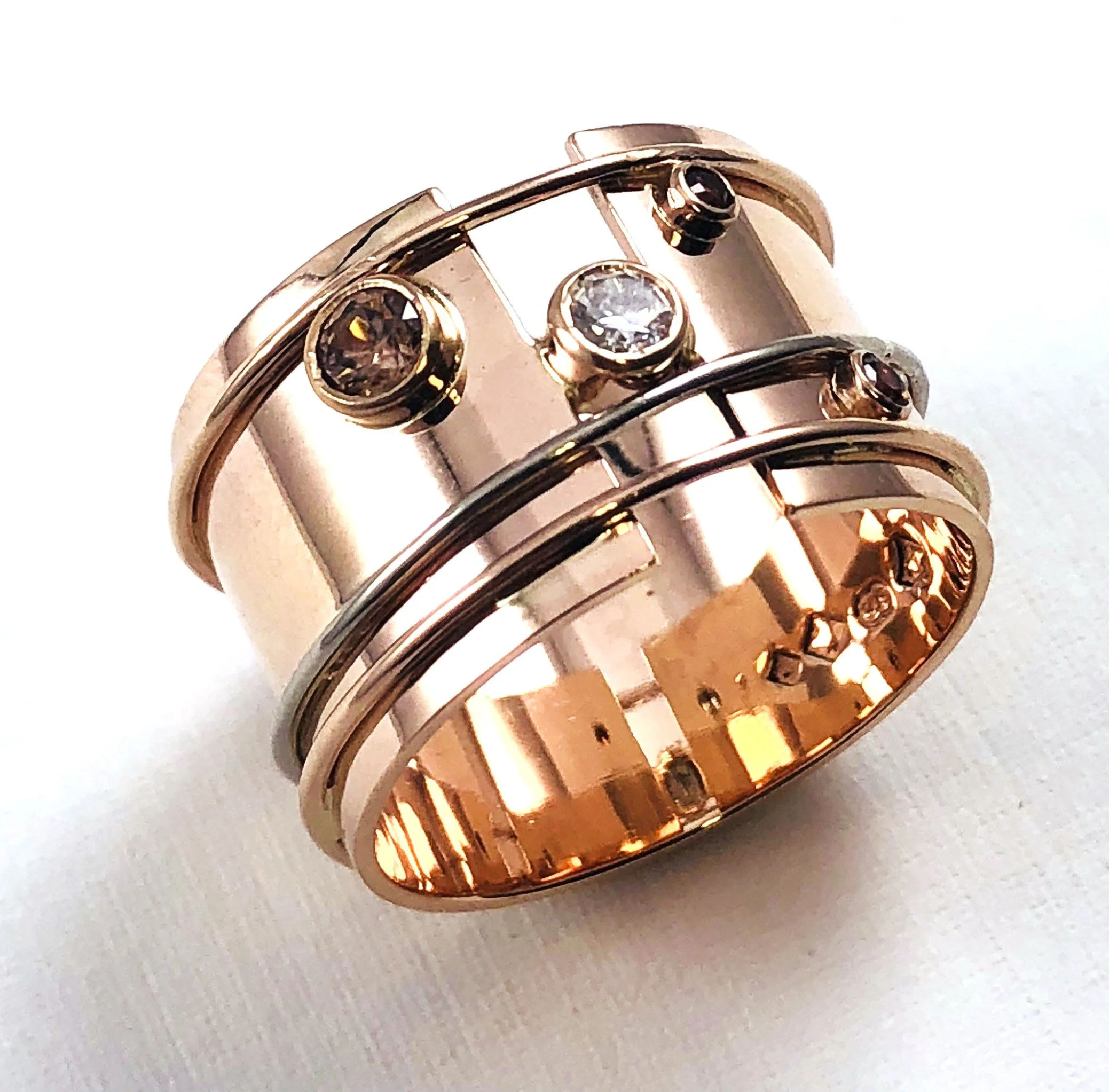 A thick rose gold ring with multiple small diamonds set in a circular pattern on a light surface.
