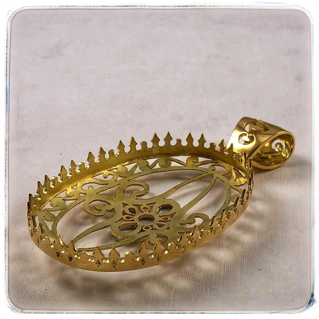 A gold-colored, ornate pendant with an intricate filigree design.