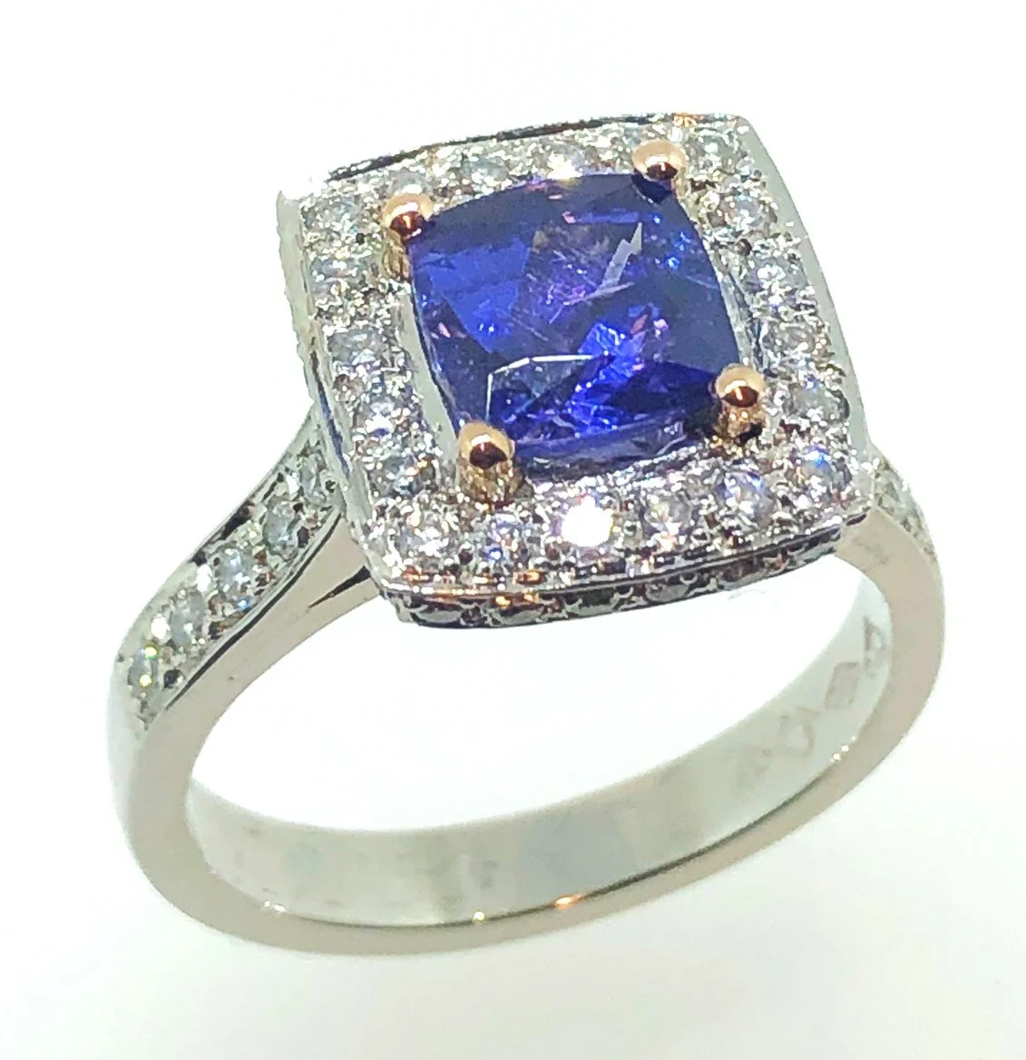 Silver ring with a large rectangular blue gemstone surrounded by small clear stones.