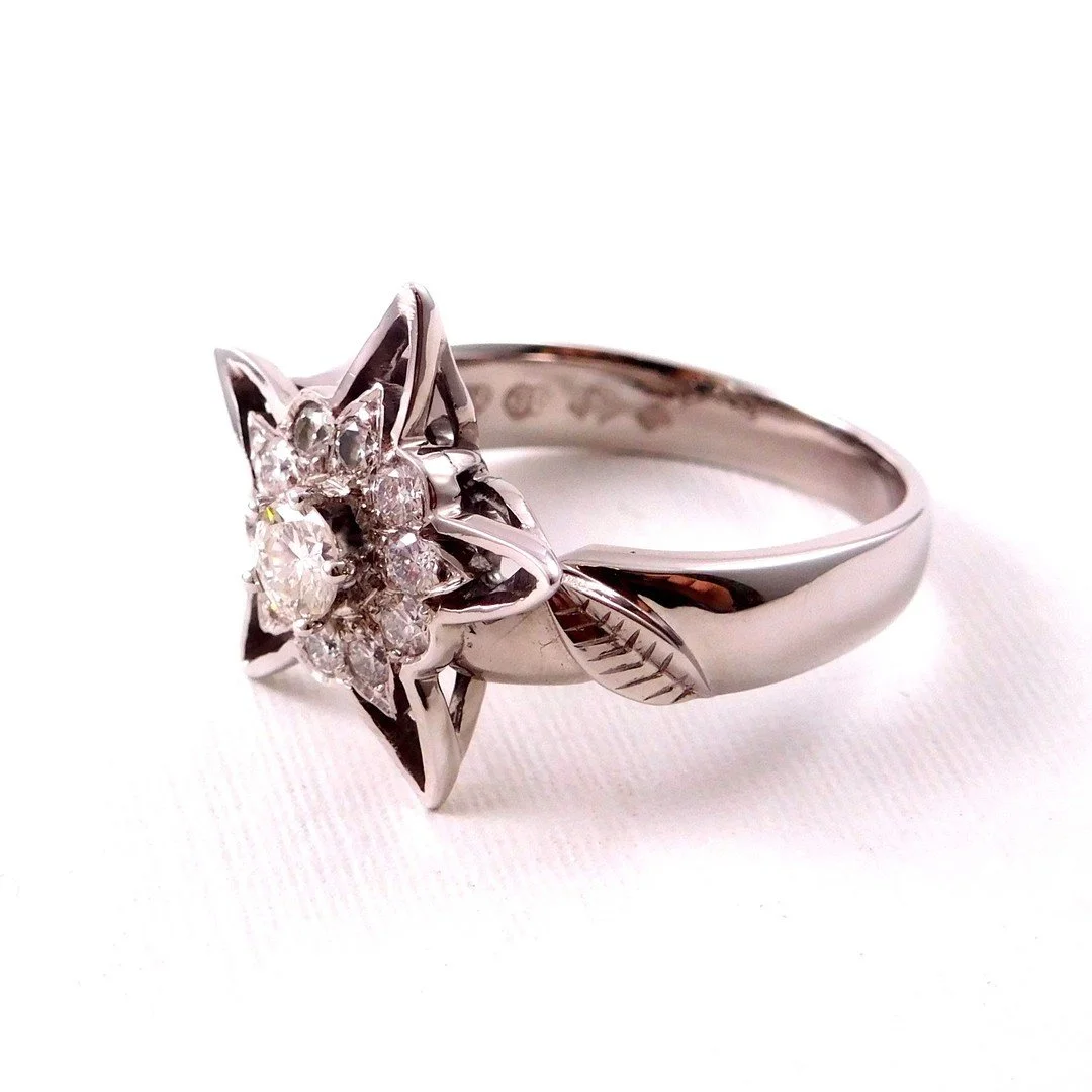 White gold ring with a star-shaped design and multiple small diamonds in the center.