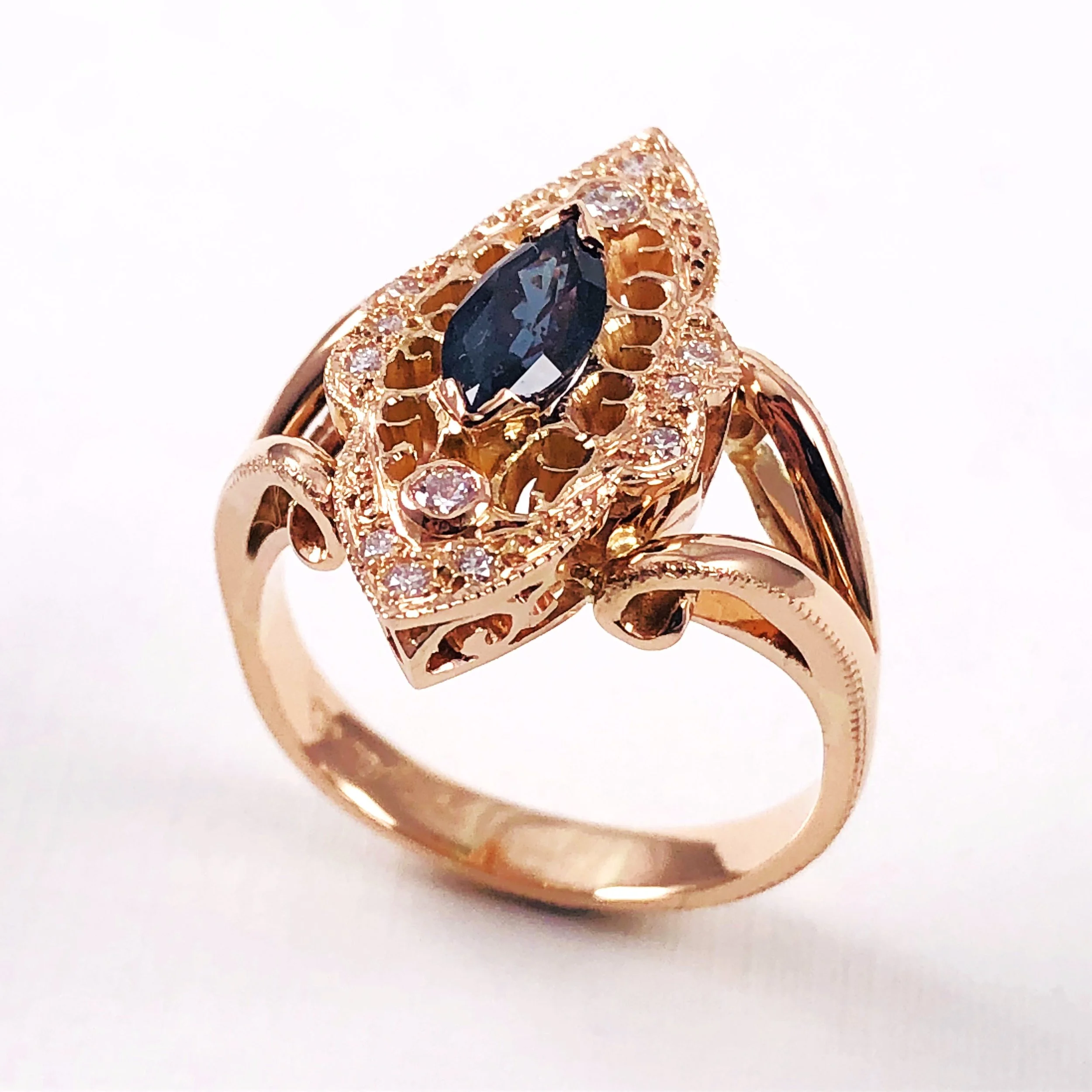 Close-up of a gold ring with a large dark blue gemstone and smaller clear stones set around it.