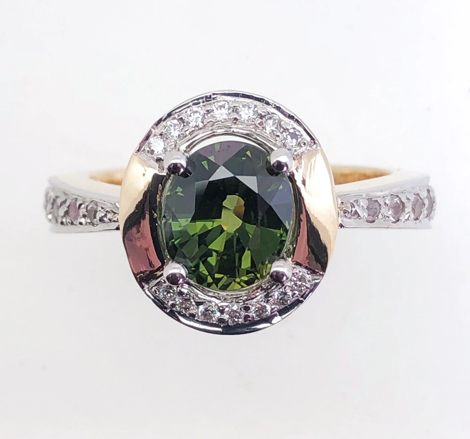 Close-up photograph of a multi-stone ring featuring a large, oval-shaped black gemstone set in a silver band with small clear gemstones surrounding the central stone.