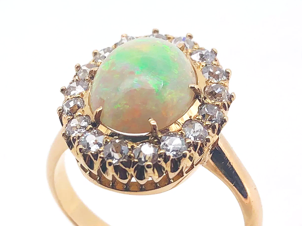 Gold ring with a central opal gemstone surrounded by small diamonds.