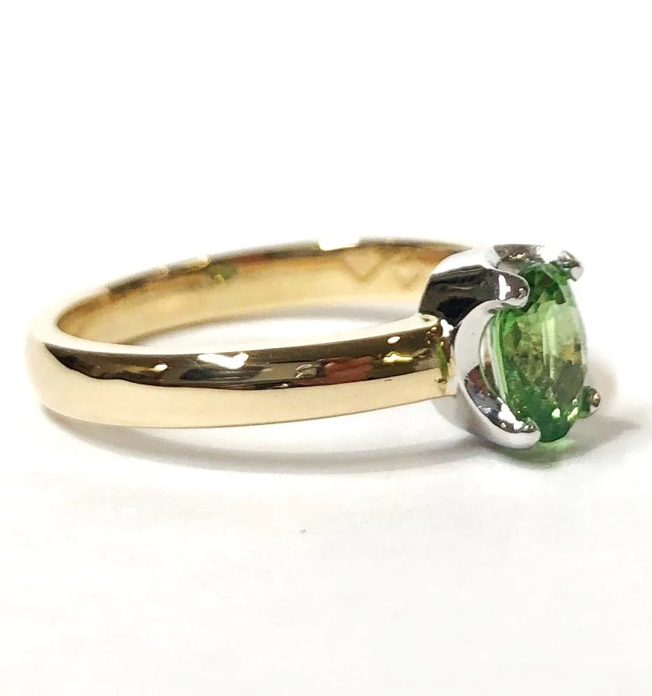 Gold ring with a green gemstone set in white gold setting.
