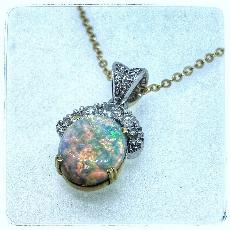 Pendant necklace with a large oval opal gemstone surrounded by diamonds