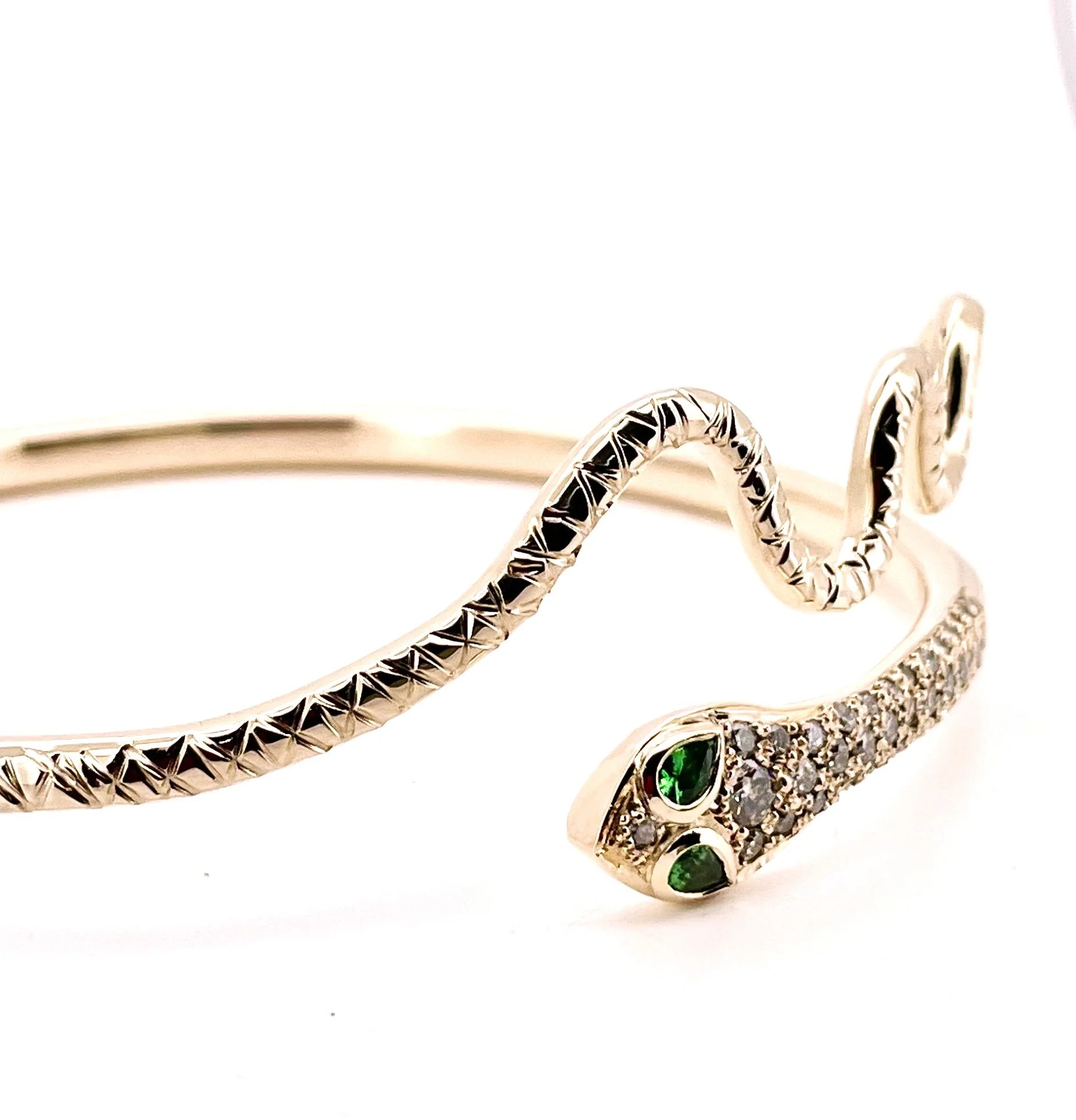 Cleopatra-inspired gold snake cuff with diamond-set head and green tsavorite garnet eyes