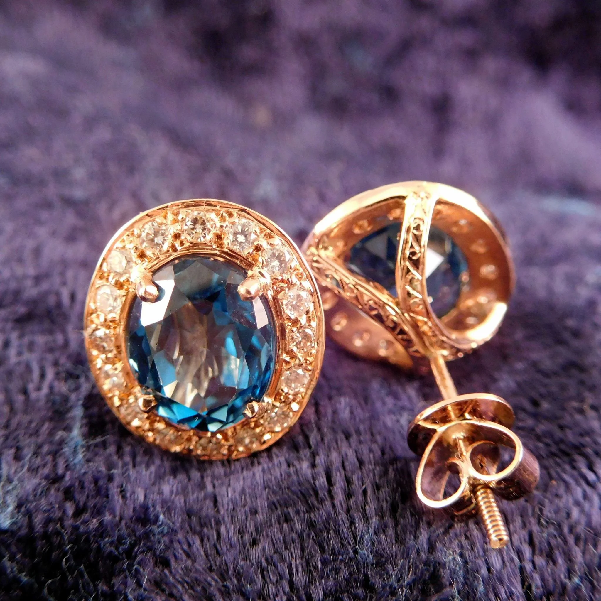 Close-up of a rose gold earrings, set with blue topaz, surrounded by diamonds. 