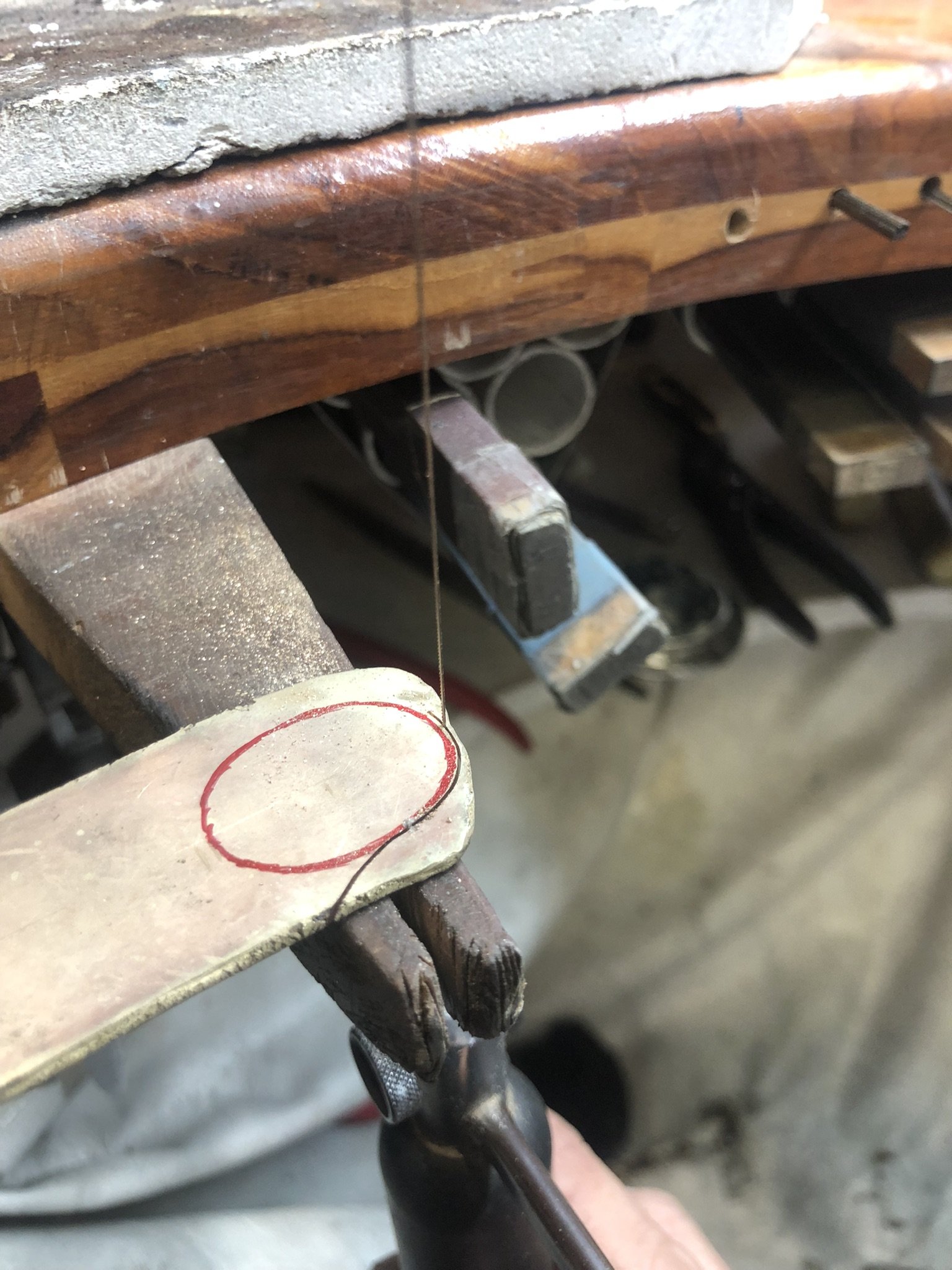 Flat piece of gold with a oval shape drawn on it, about to be cut-out 