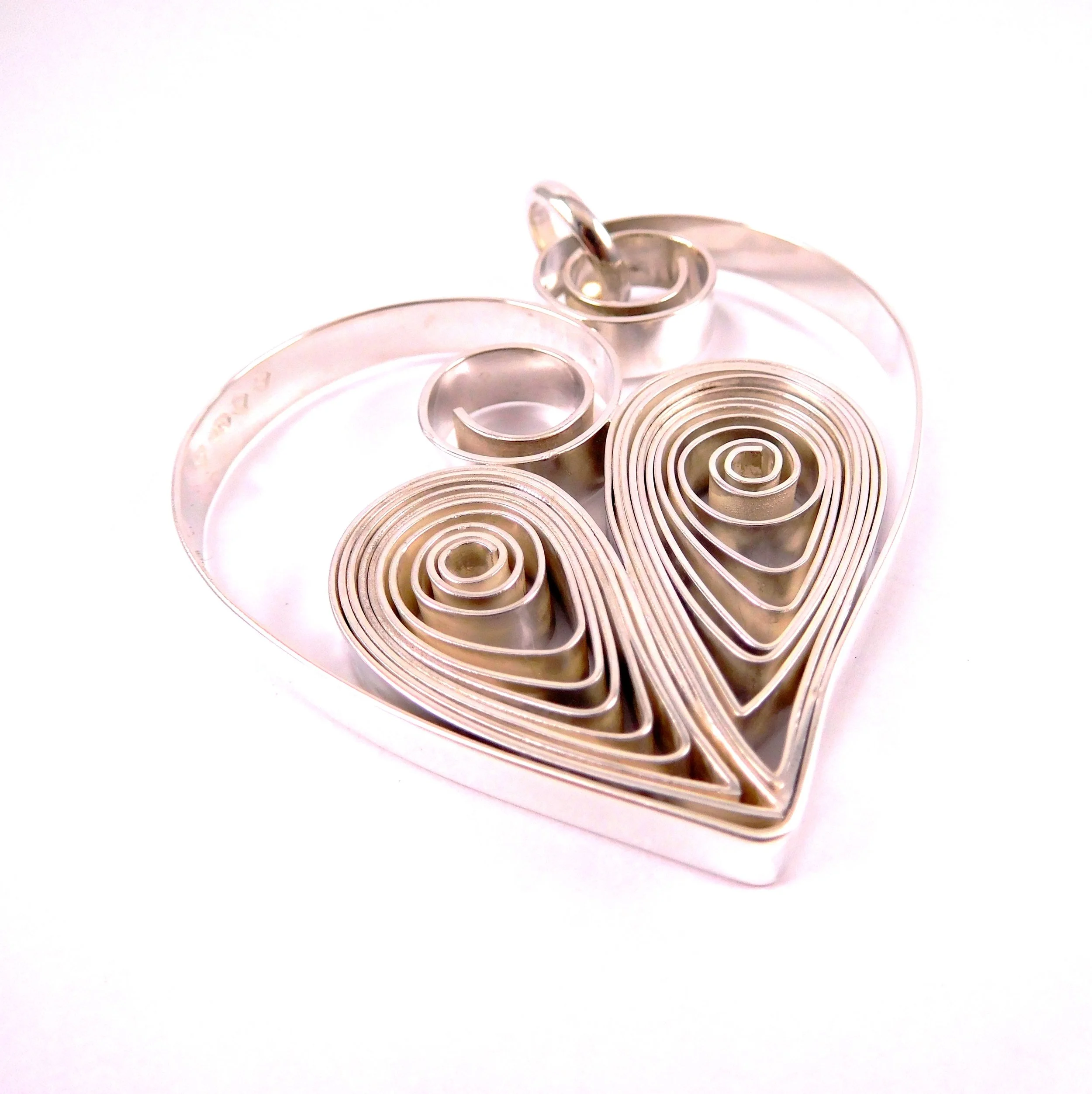 A scroll-like silver heart-shaped pendant. 