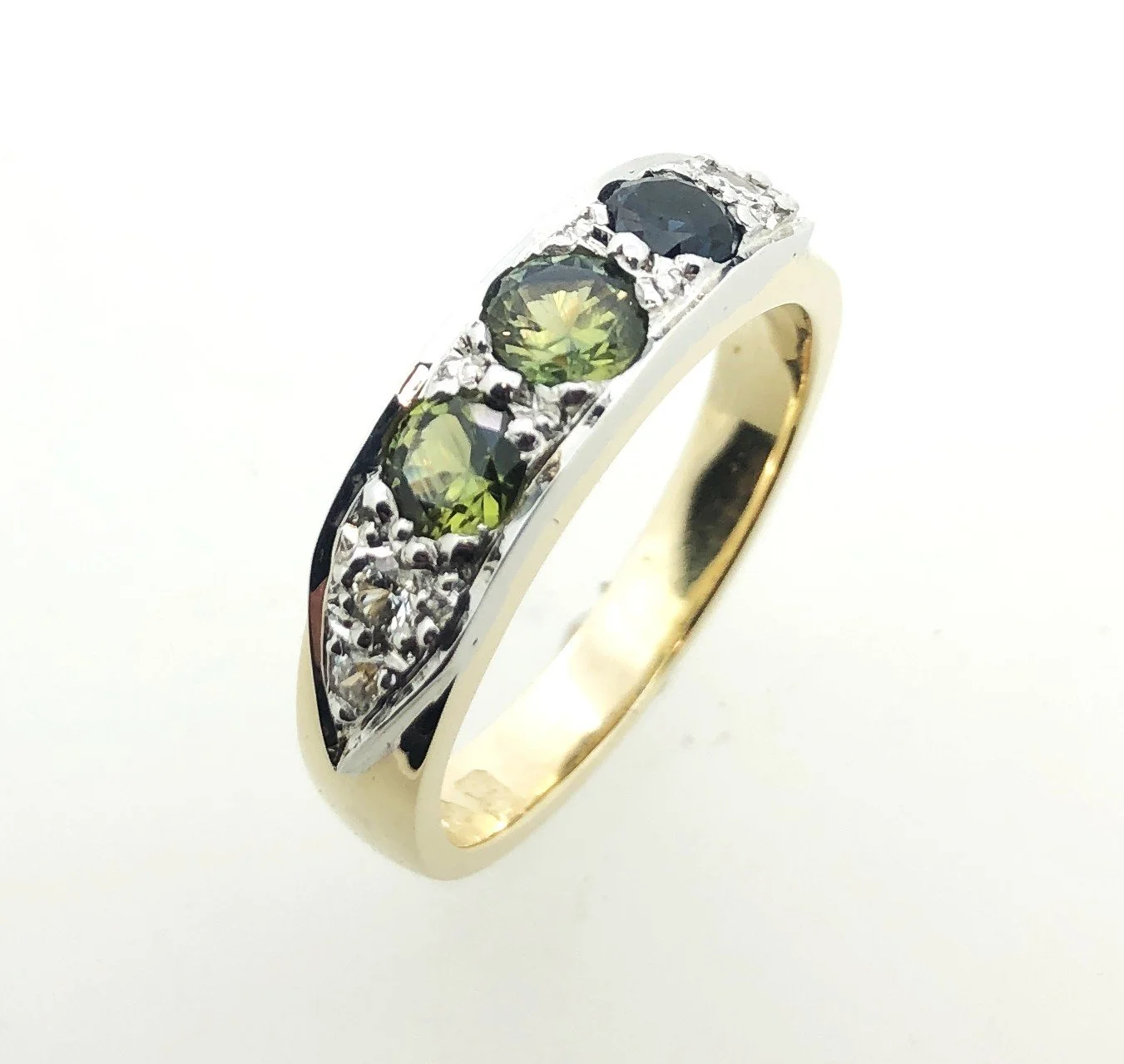 Gold ring with black and green gemstones and small diamonds embedded around the band.