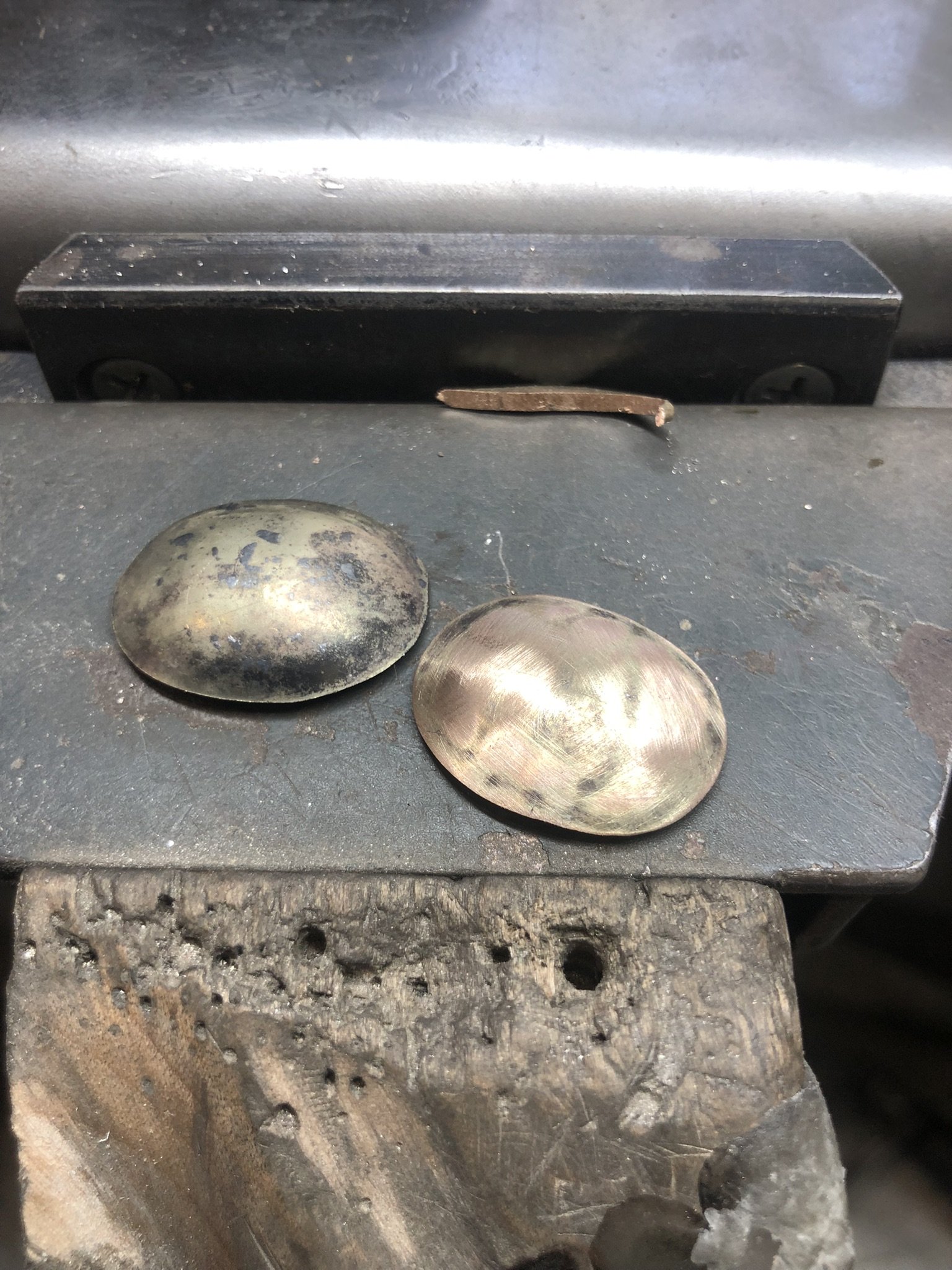 Close-up of a metal workbench with two smooth, oval metal pieces