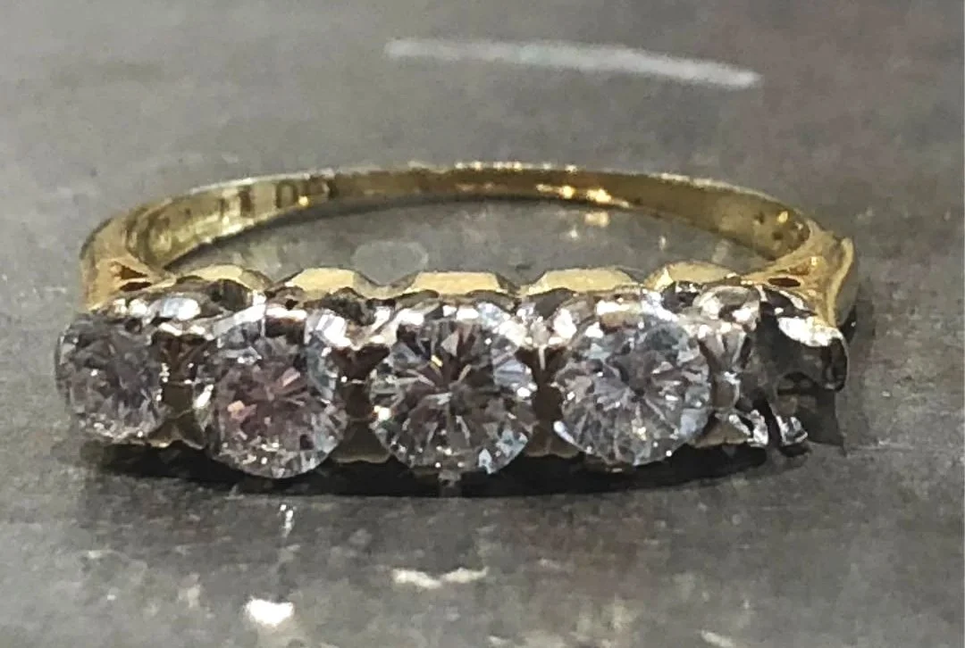 A gold ring with seven large diamonds set in a row, needing repair.