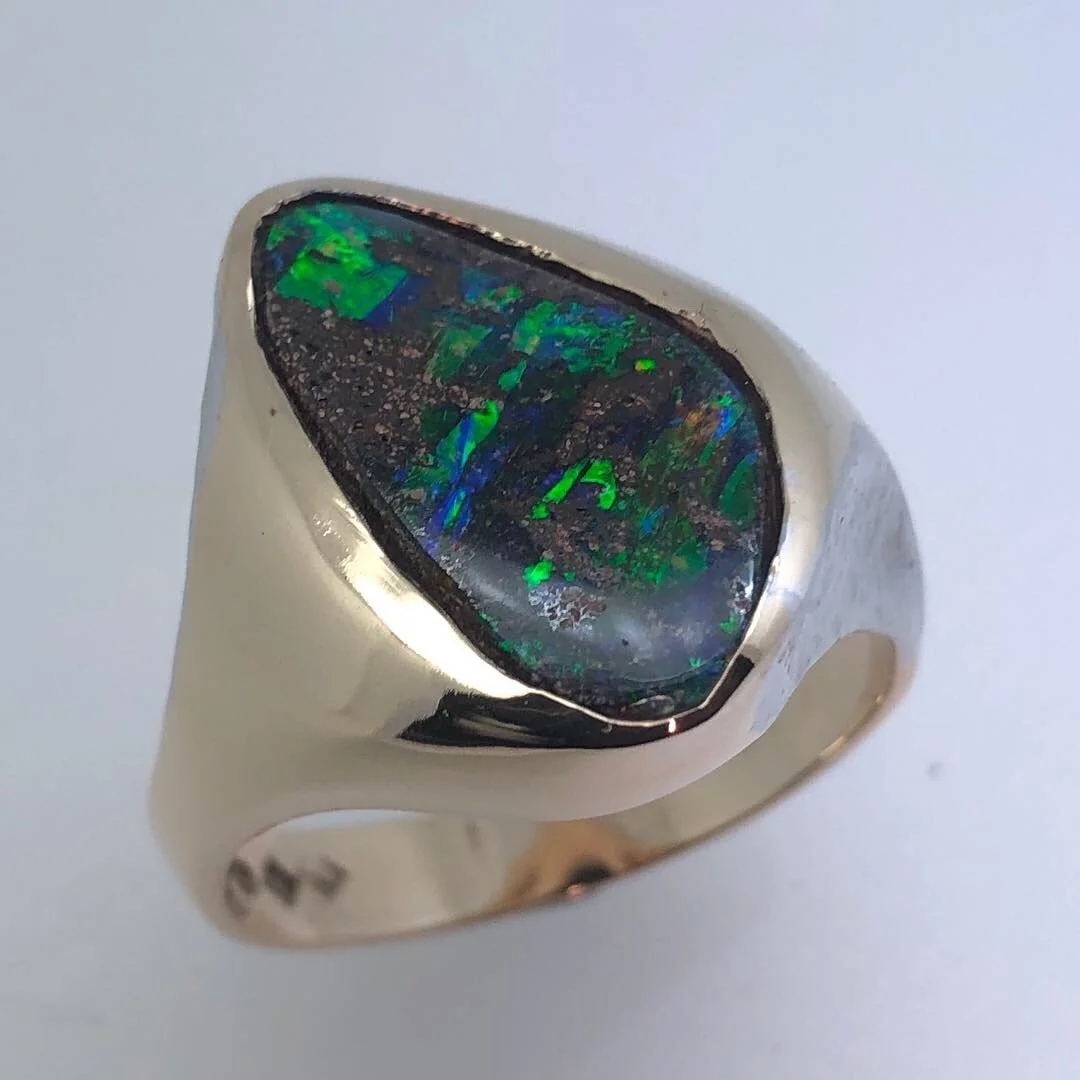 A silver ring with an oval-shaped black and green opal gemstone.