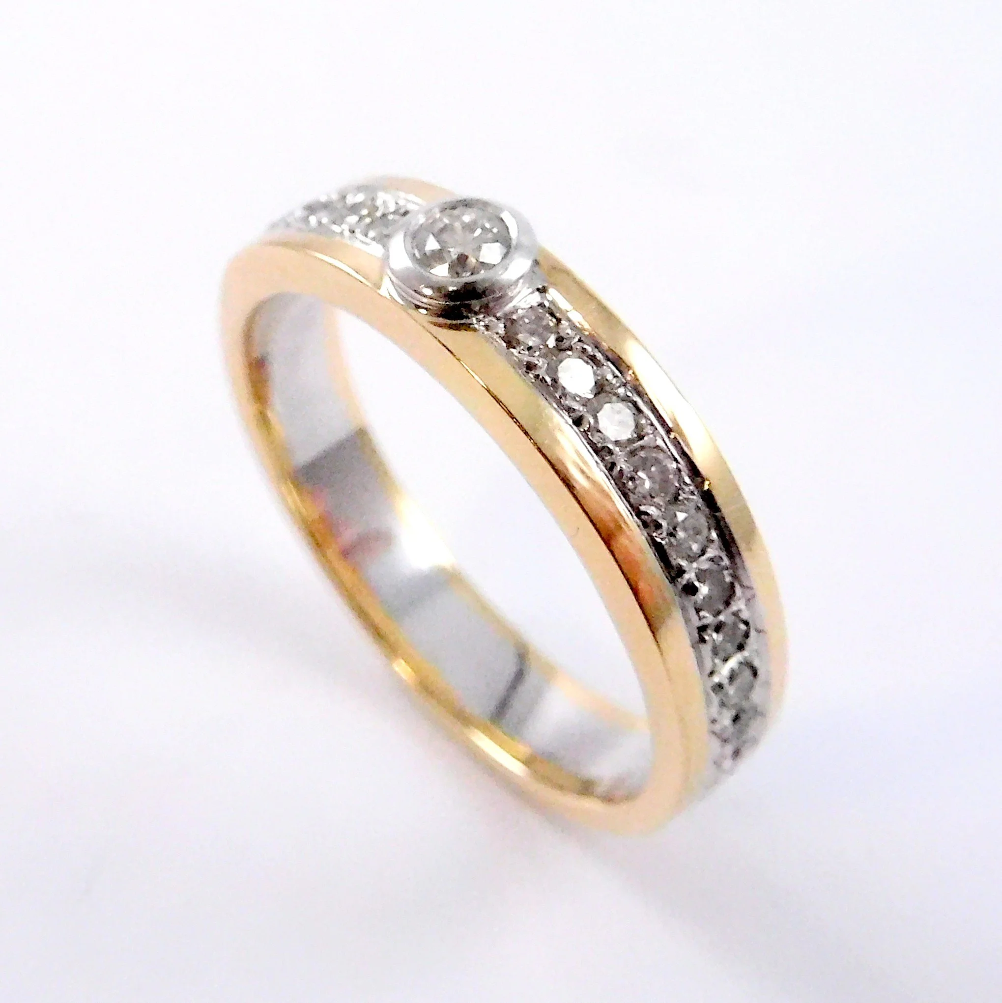 Close-up of a gold ring with embedded diamonds, set against a white background.