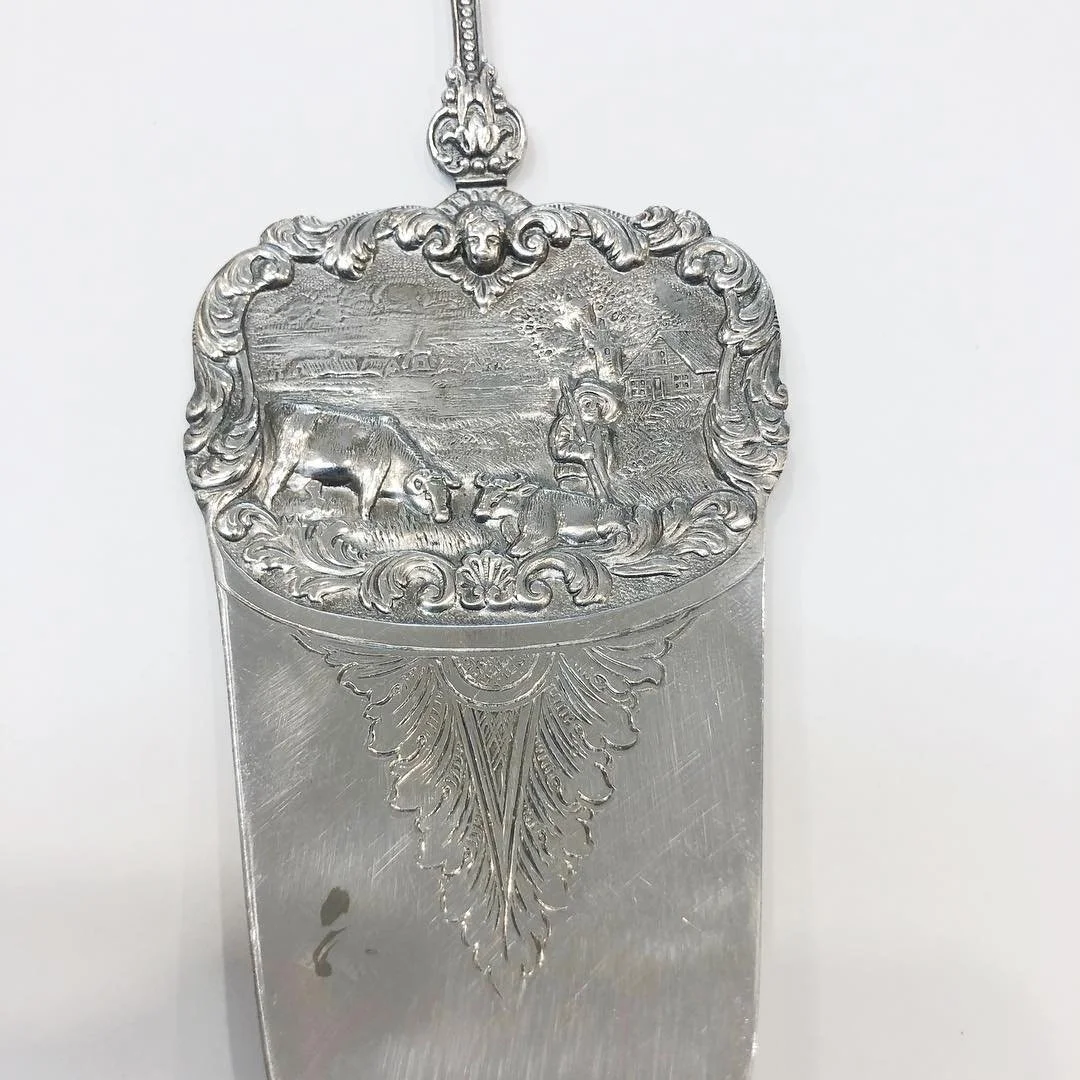 Silver decorative item with engraved rural dutch landscape scene, after being repaired.