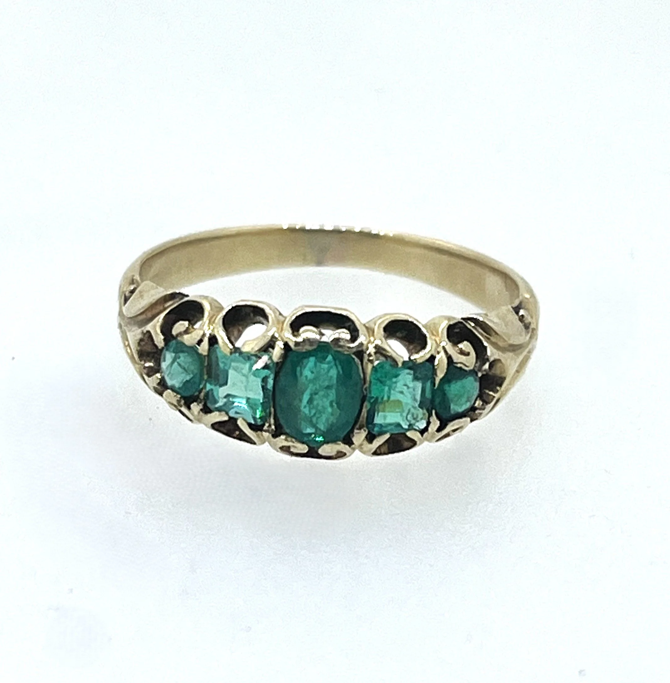 A silver ring with emerald gemstones arranged in a cluster design.