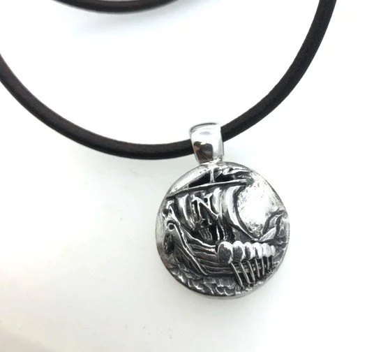 Metal viking ship themed pendant , attached to a black cord necklace.