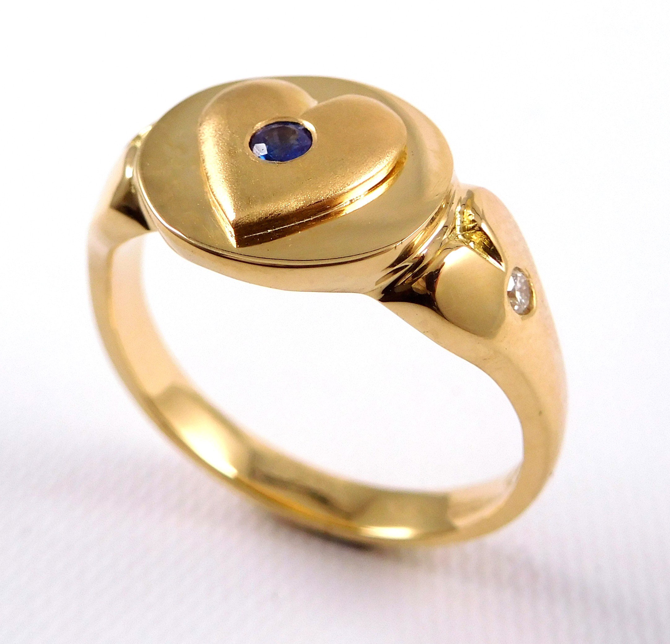 Gold ring with a heart-shaped top and a blue gemstone in the center