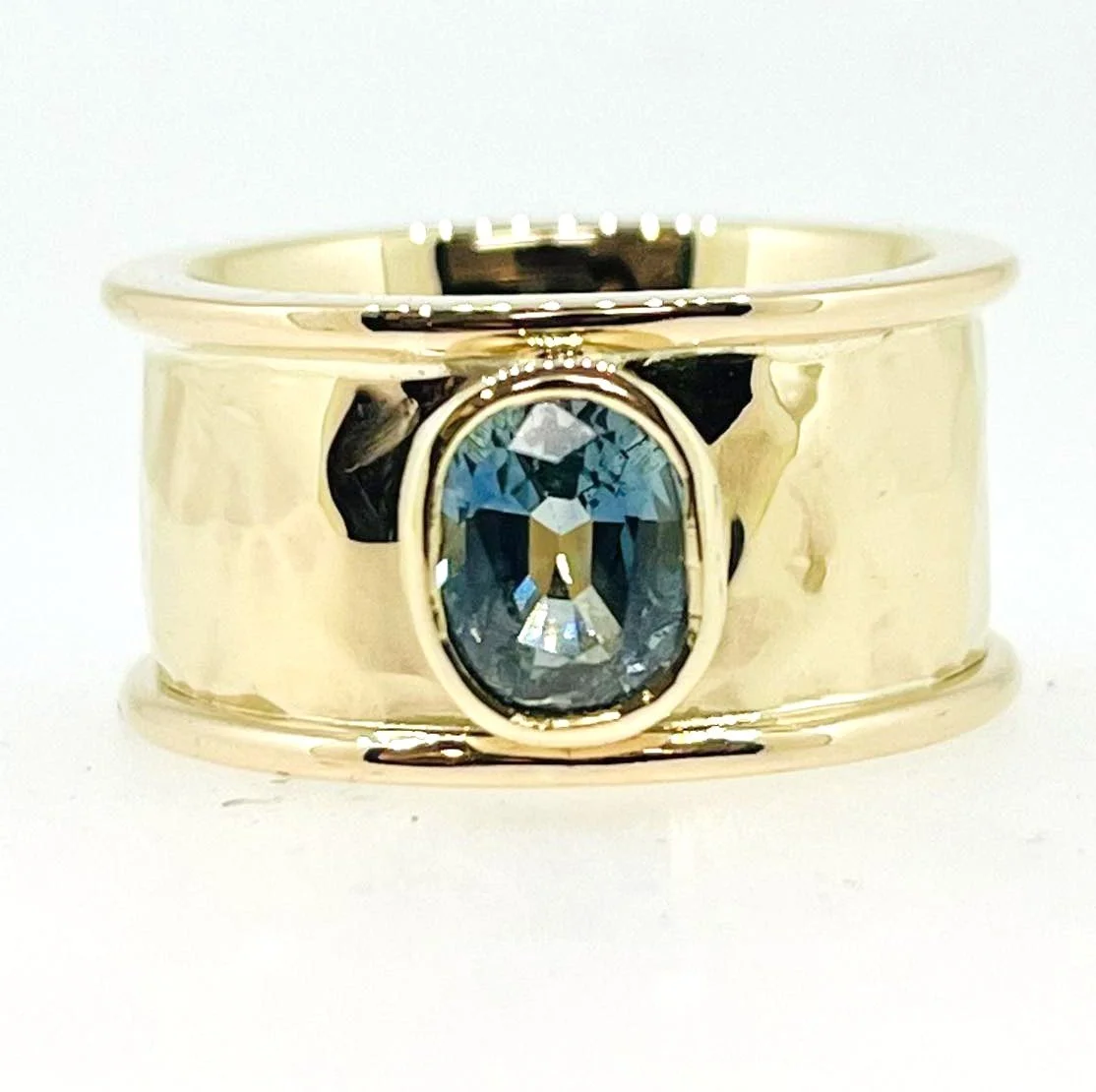 A wide gold ring with a large oval blue gemstone in the center.