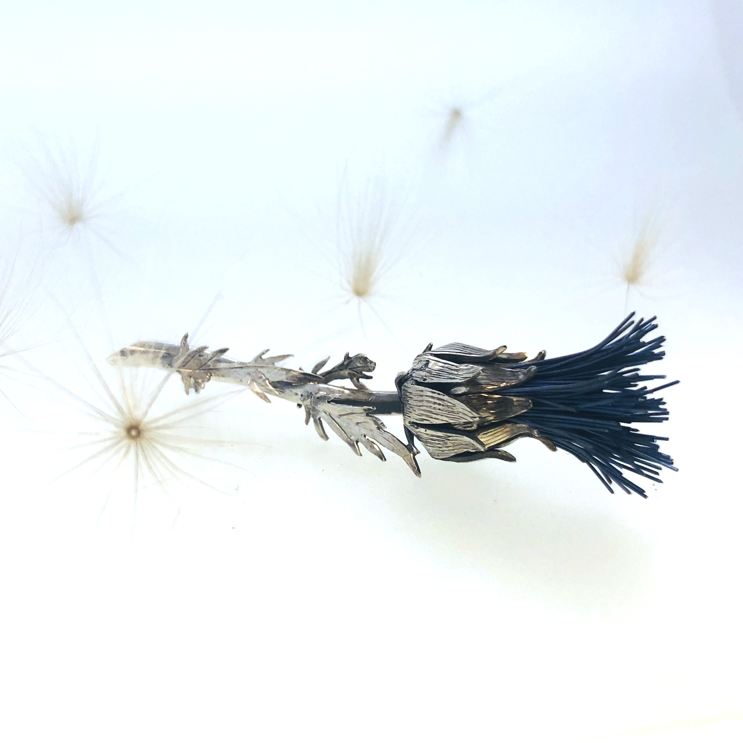 A realistic silver and titanium thistle brooch. 