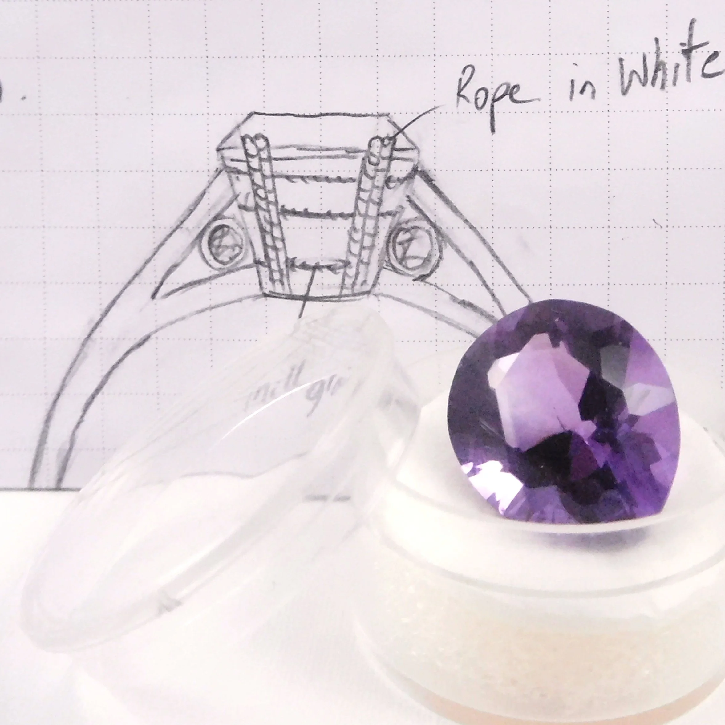 Pear-cut amethyst beside ring design sketch showing rope-style claw setting