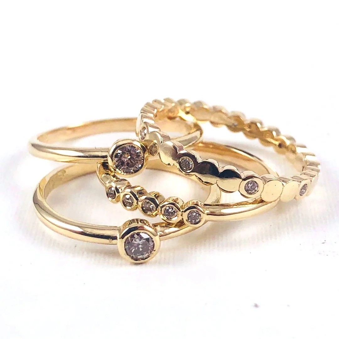 A collection of gold rings with small embedded gemstones, arranged on a white background.