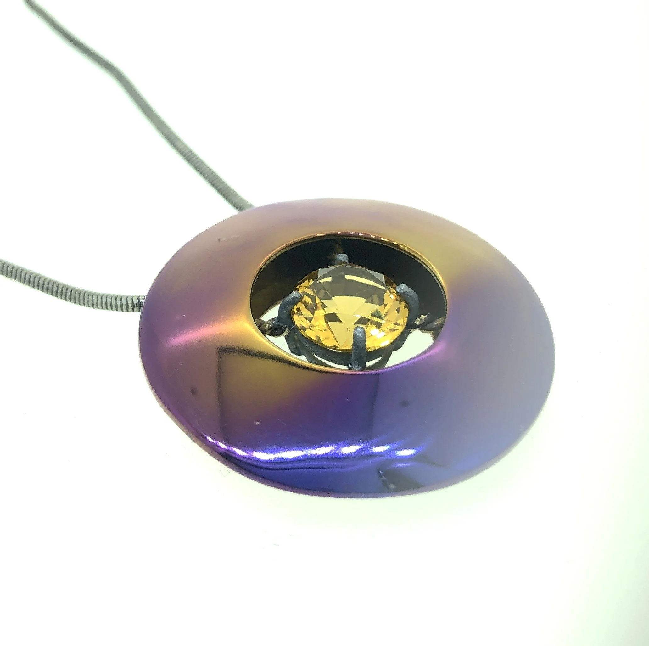 A titanium necklace with a large yellow citrine gemstone. 