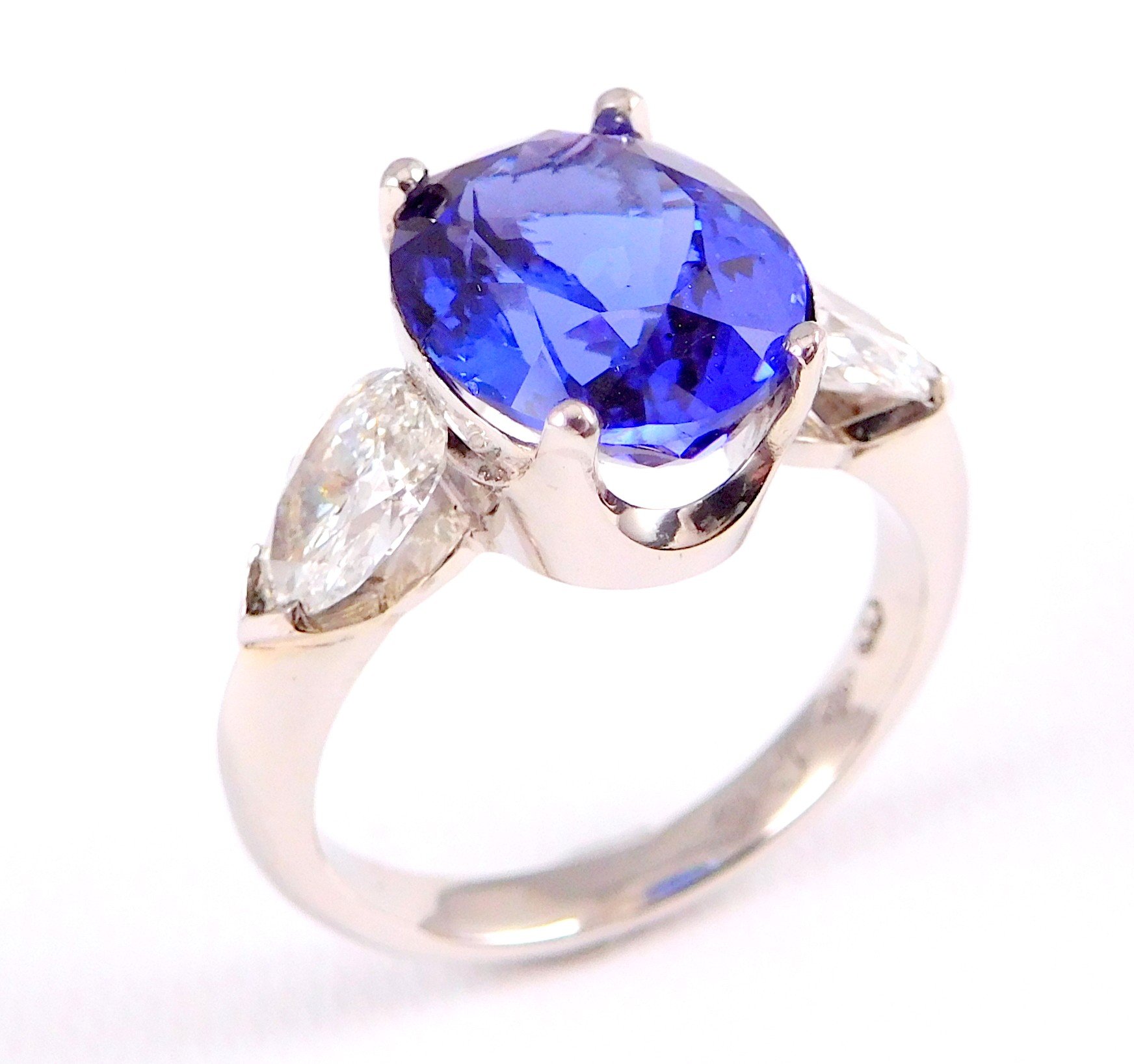 Close-up of a ring with a large blue gemstone and smaller clear gemstones on the sides, set in a silver band.