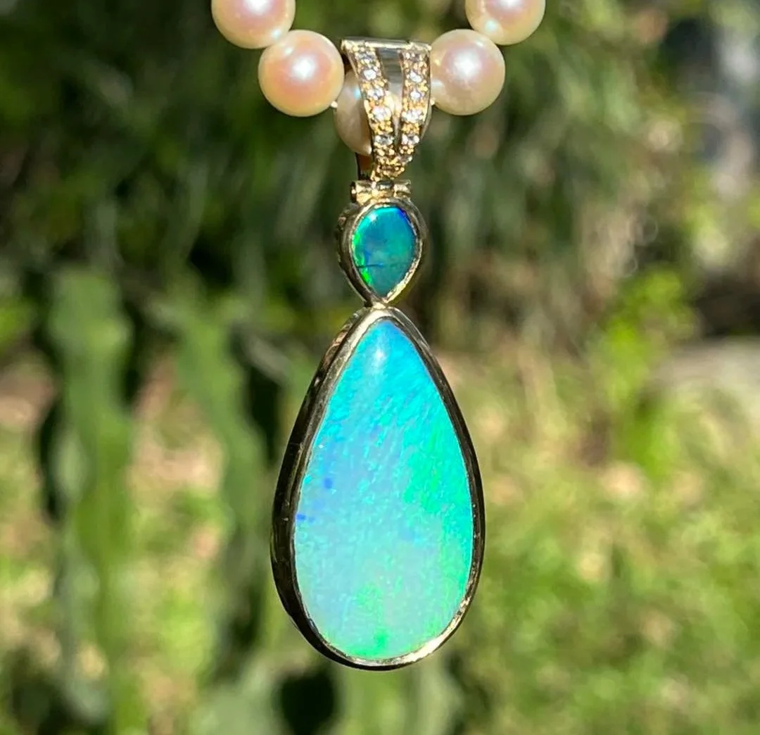 Pearl necklace with a large teardrop-shaped opal pendant, set in gold with a small green opal above it, hanging from a string of pearls.