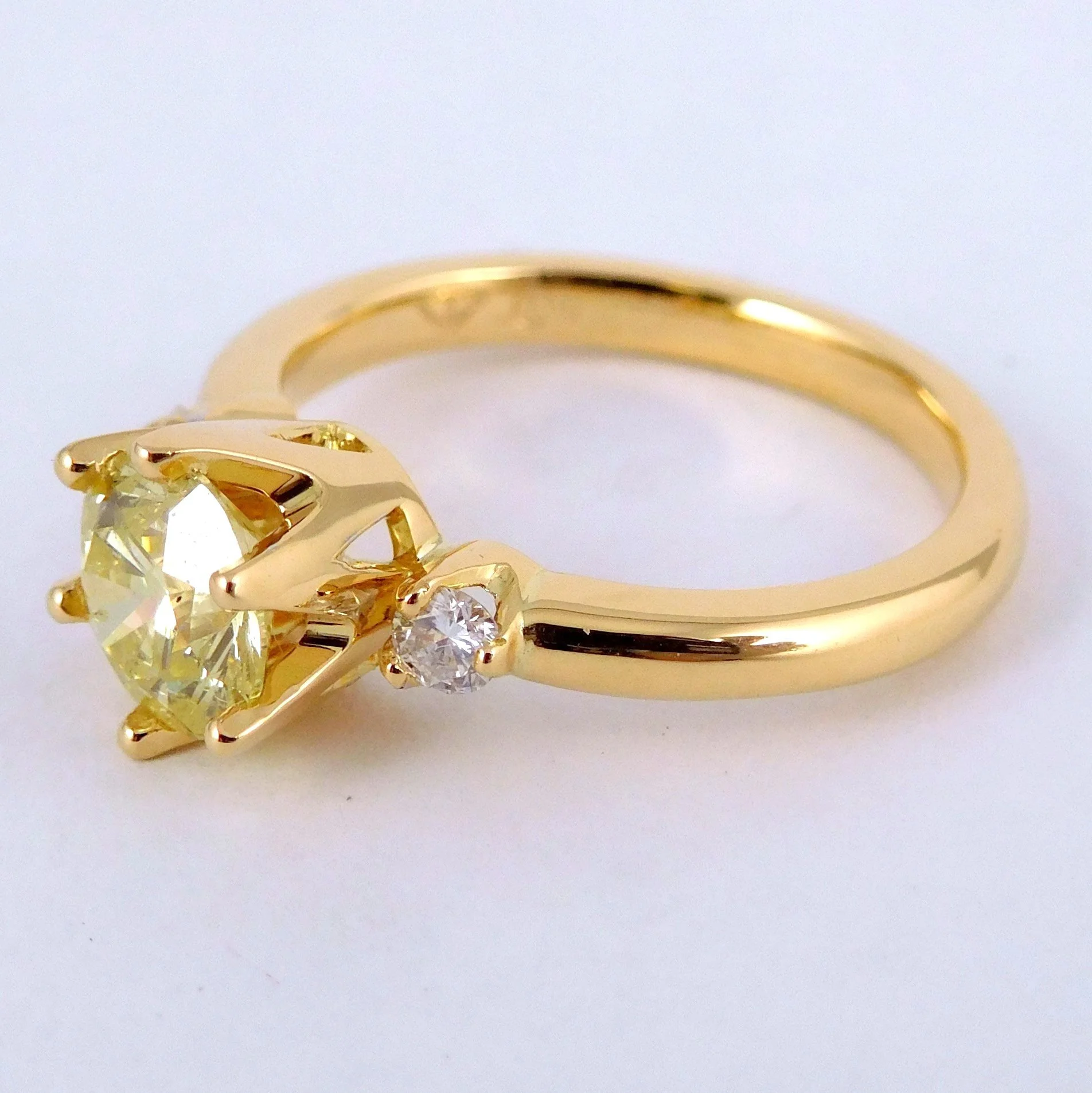 A gold engagement ring with a large central diamond and smaller diamonds on the band, set against a plain white background.