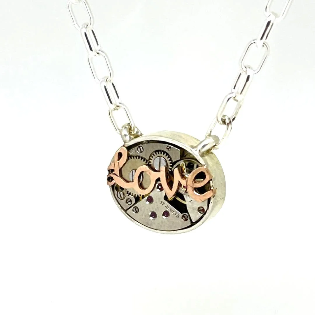 Necklace with a round pendant featuring mechanical watch gears and the word 'love' in gold-colored script.