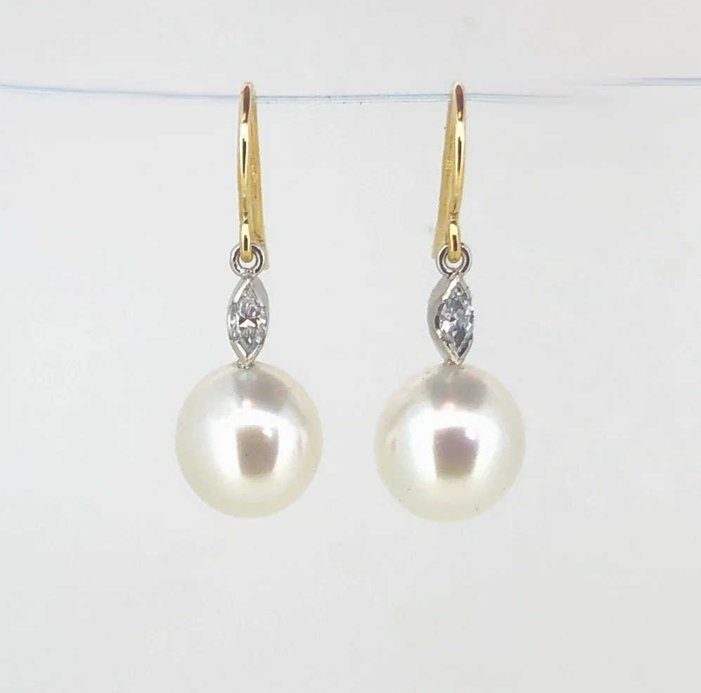 Pair of pearl drop earrings with small diamond accents on a thin gold hook.