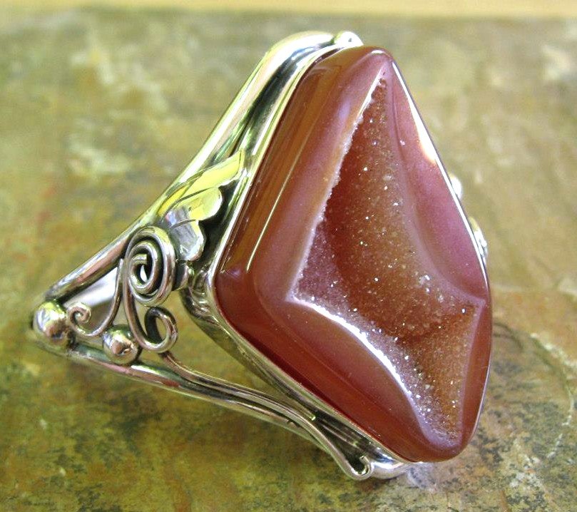 Silver cuff with a large, triangular, reddish crystal stone.