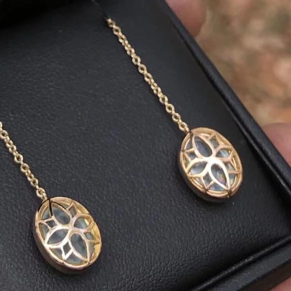 Gold earrings, resting on a black jewelry box.