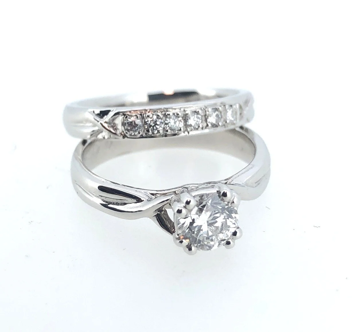 Two white gold rings, one with a central diamond and the other with small diamonds along the band.