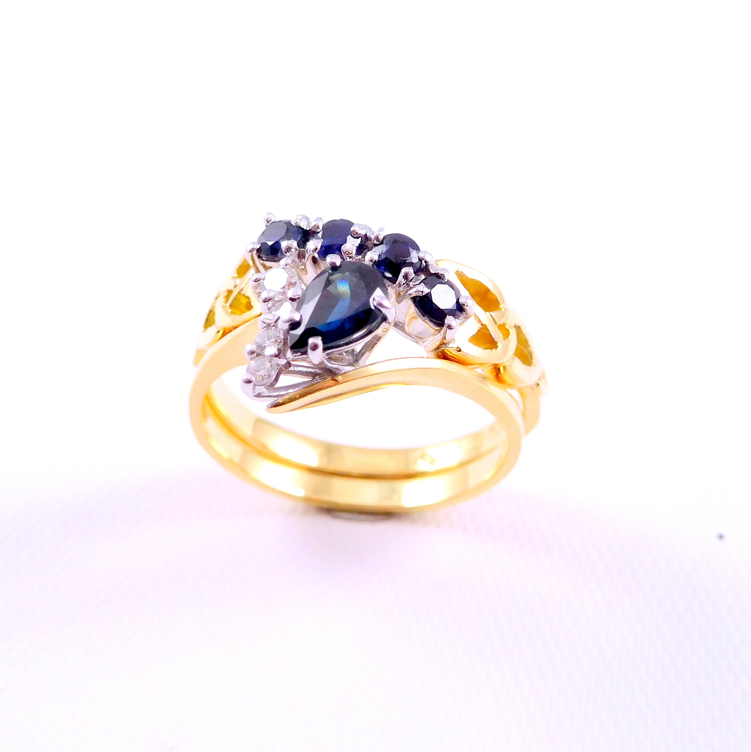Gold ring featuring multiple black gemstones set with small clear stones arranged in a floral pattern.