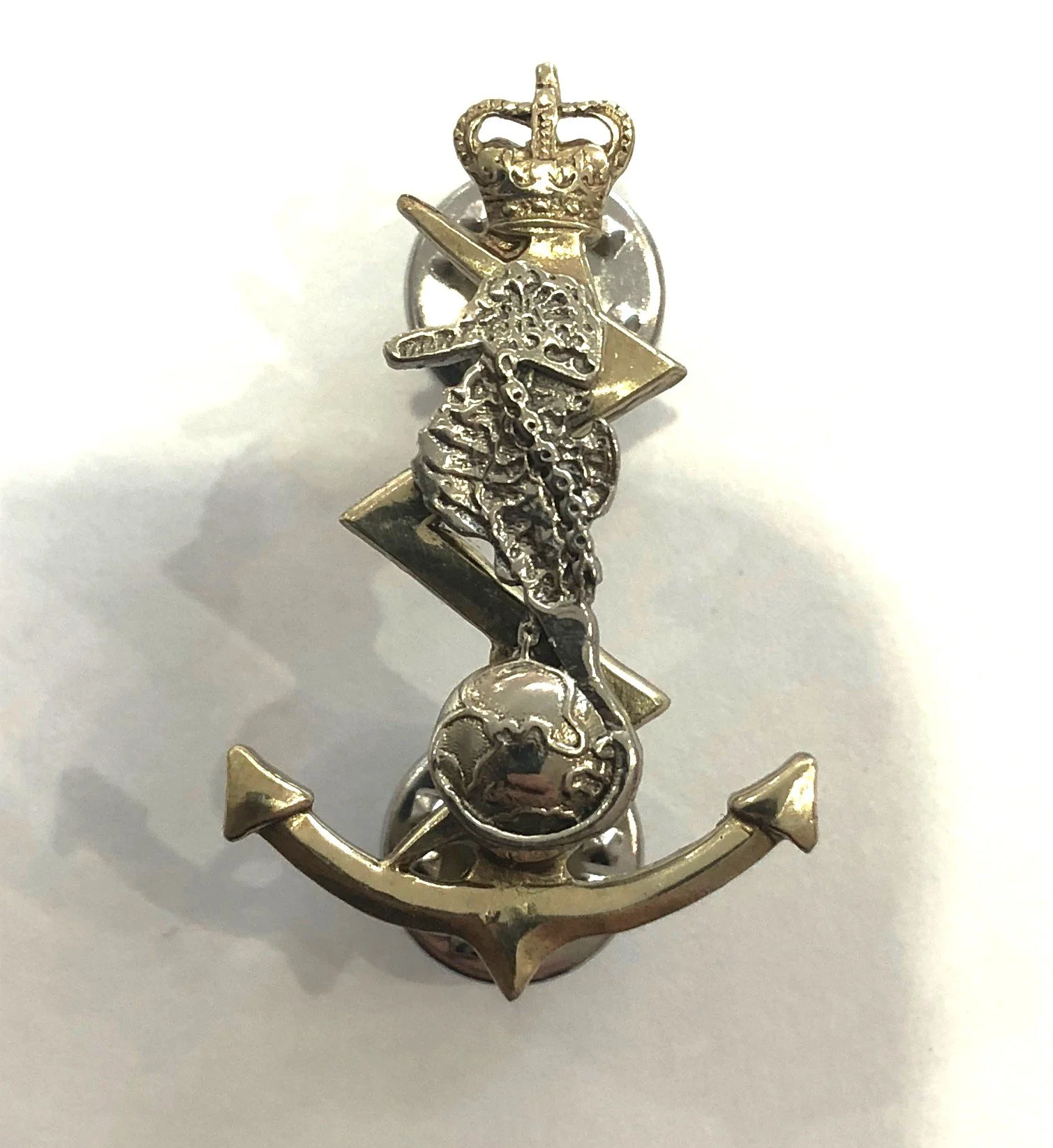 Close-up of a decorative metal object featuring an anchor shape with nautical-themed charms, including a skull, a chain, and a lion's head.