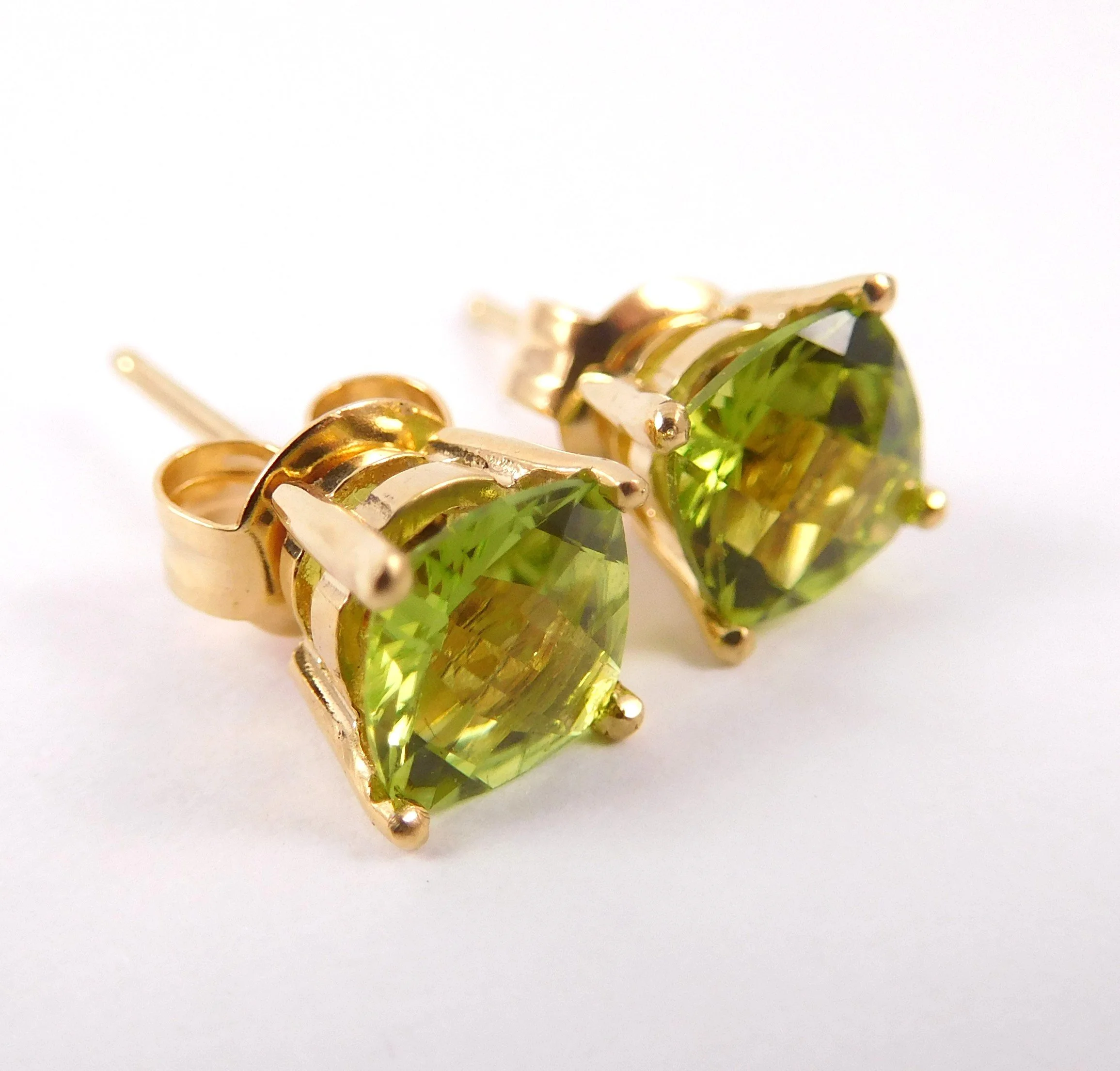 Close-up of a gold earrings with a large green gemstone set in the center