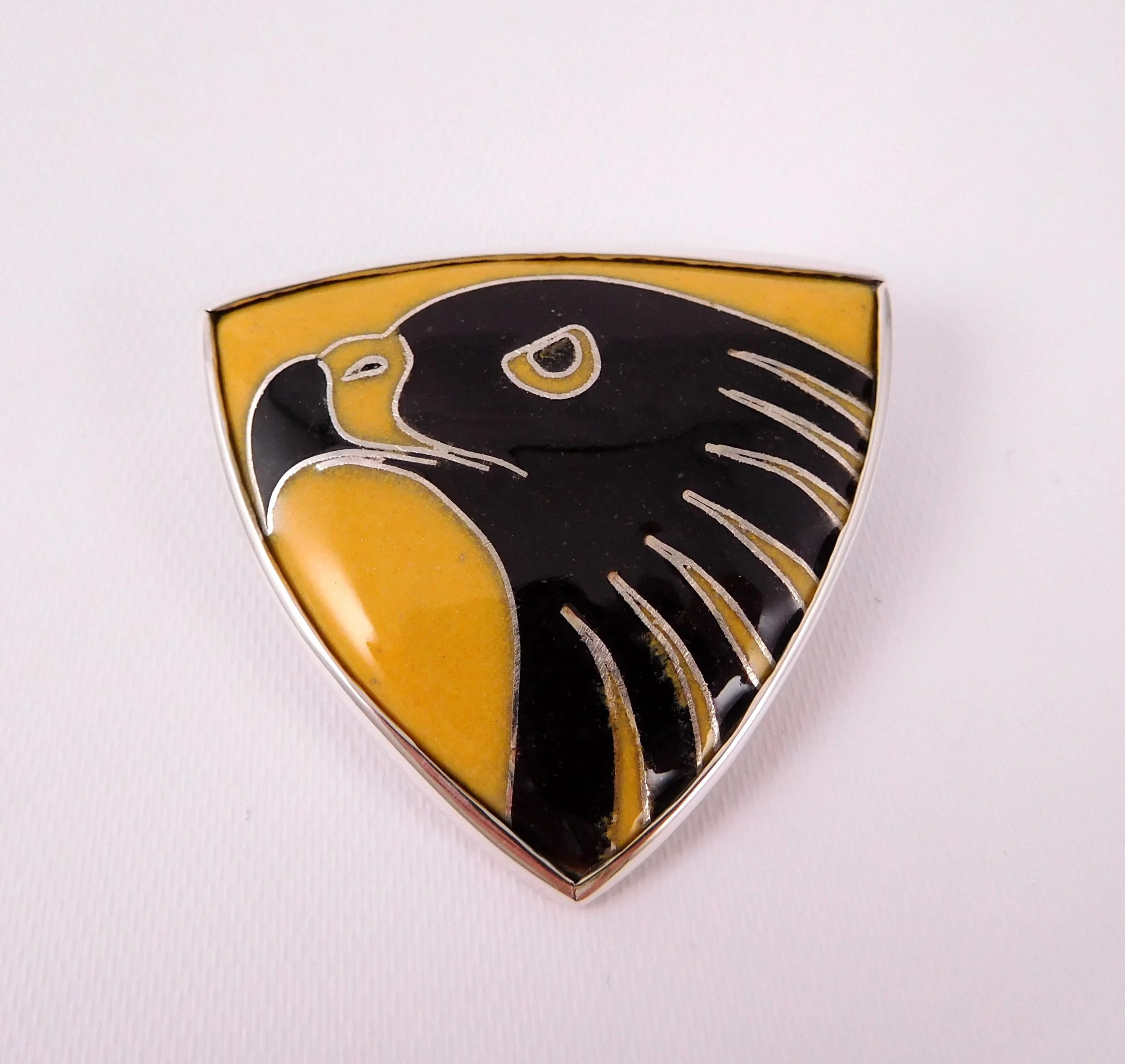 Close-up of a gold and black badge brooch with a stylized eagle