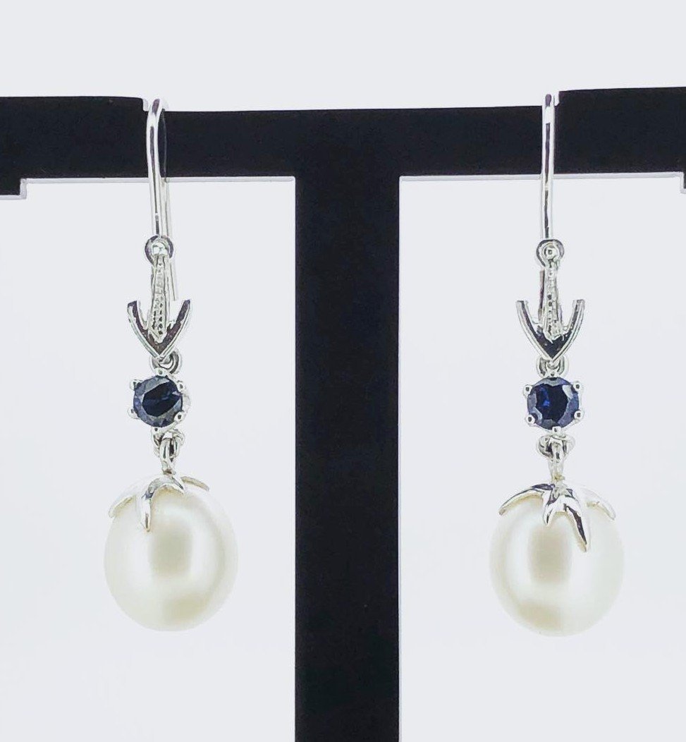 White gold  earrings featuring dark blue sapphire gemstones and pearl accents
