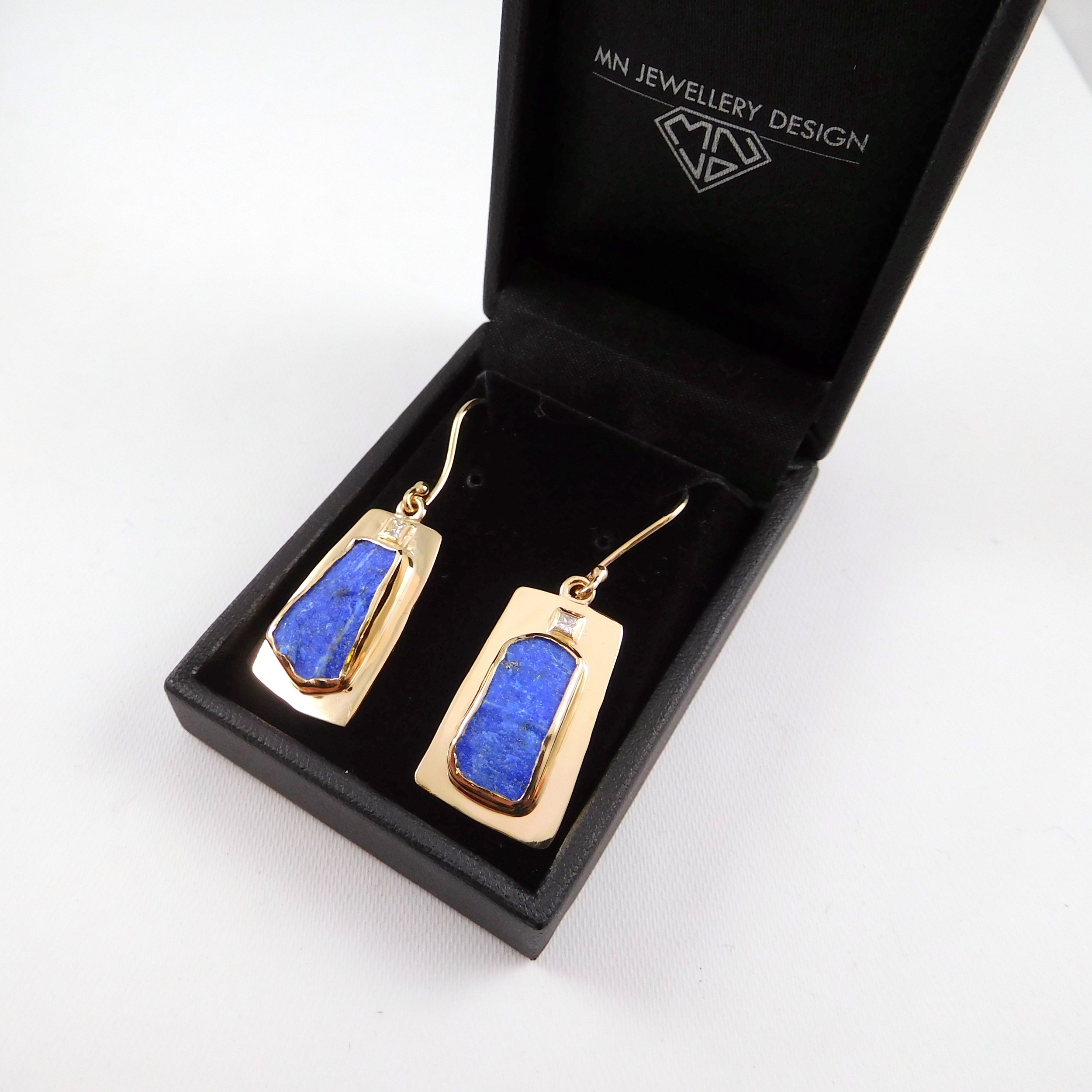 Open black jewelry box with gold and blue stone earrings