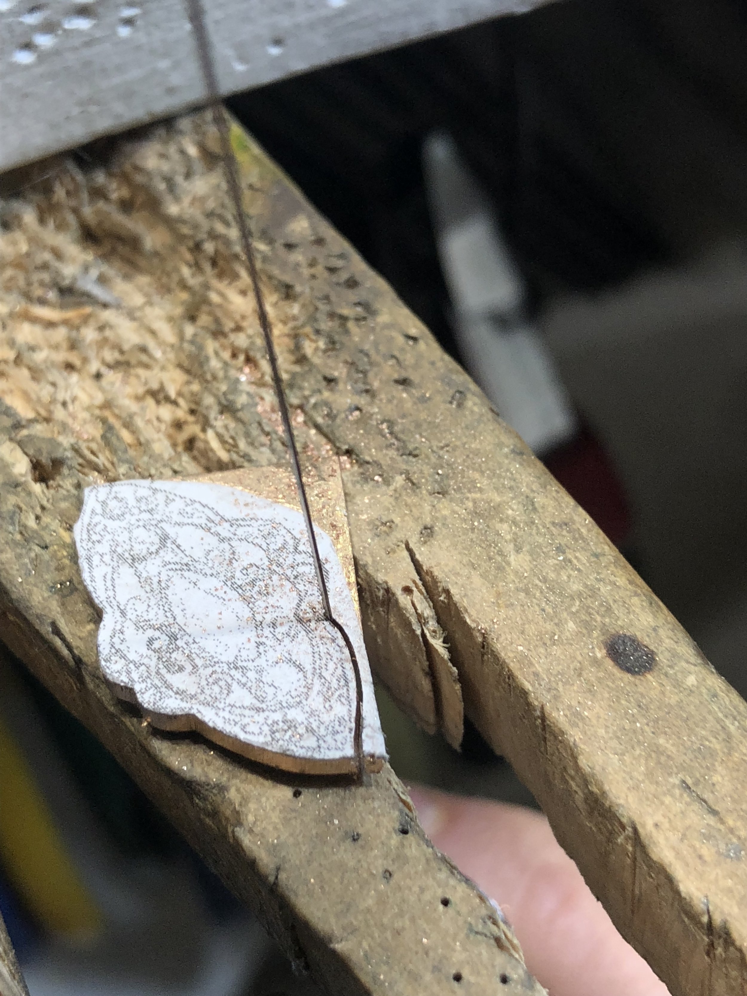 Hand piercing the rose gold ring design from a drawn template