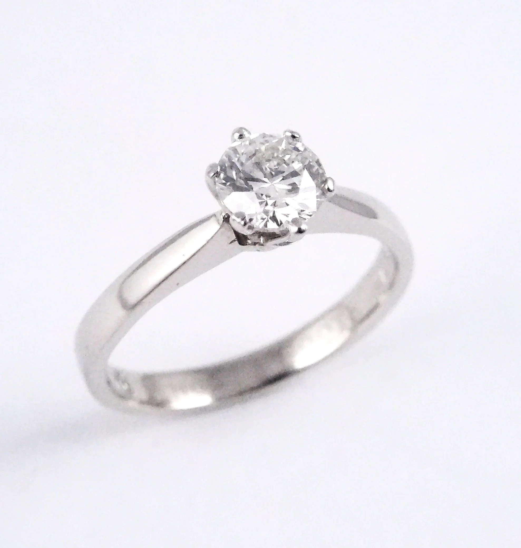 Close-up of a diamond solitaire engagement ring with a large round-cut center stone in a prong setting on a silver band.