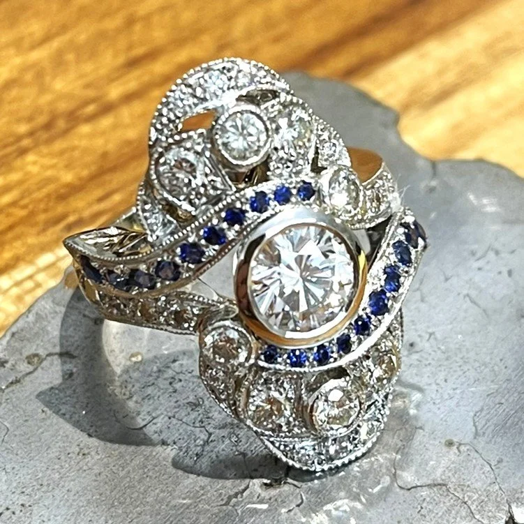 Finished platinum Art Deco dress ring photographed on slate with diamonds and blue sapphires